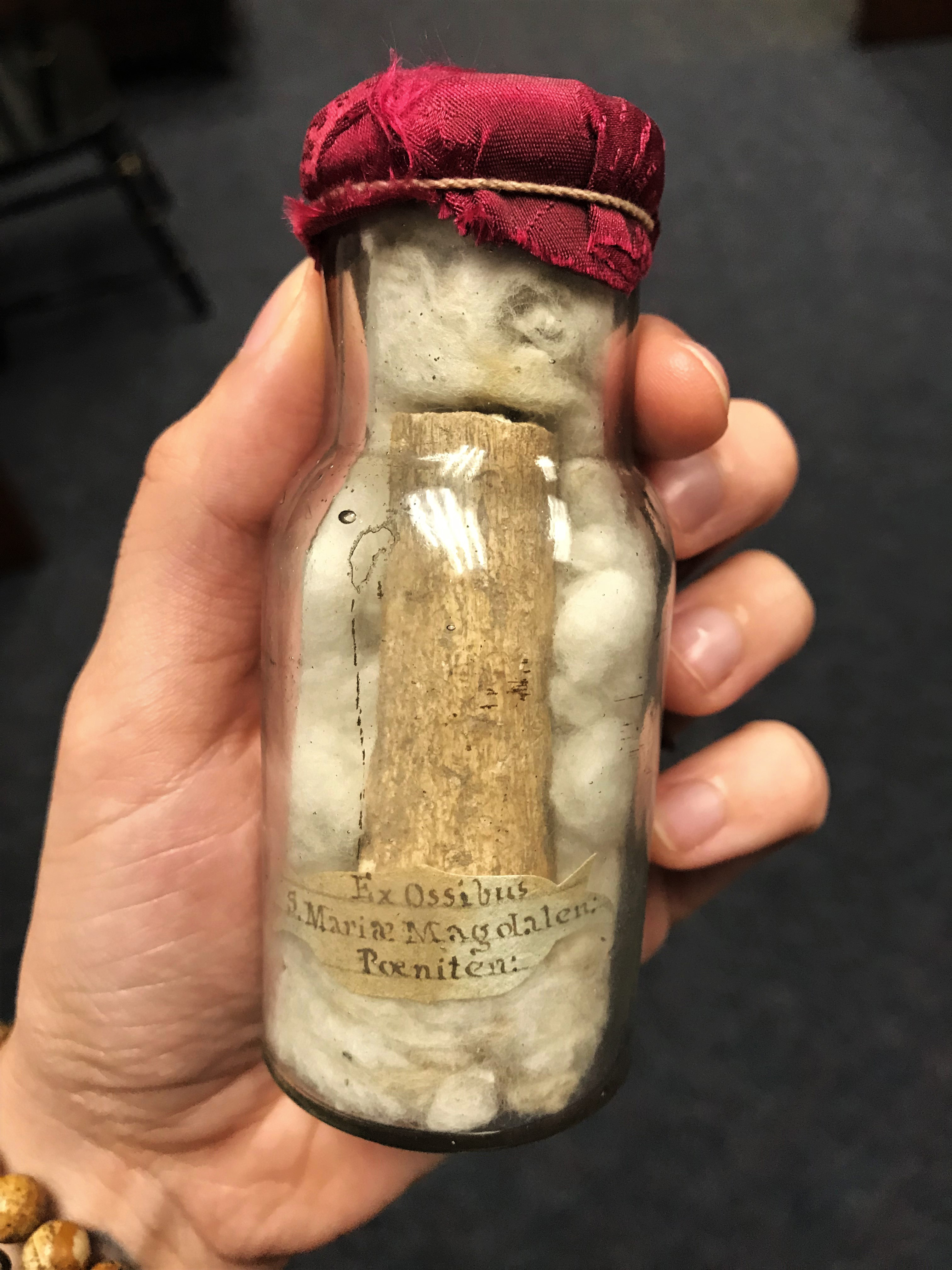 clear glass bottle containing bone fragment