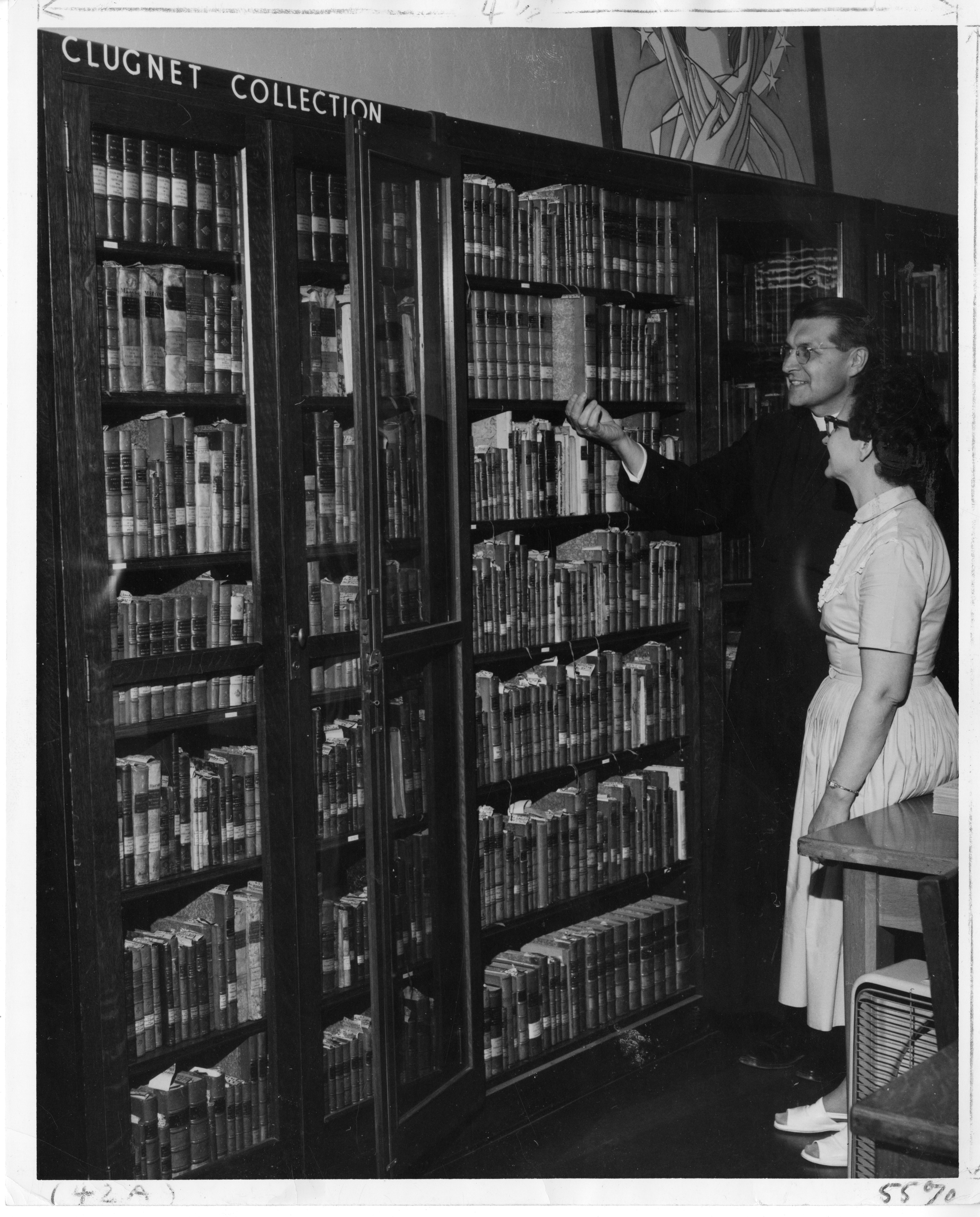 Fr. Philip C. Hoelle, S.M., director of the Marian Library, showing the Clugnet Collection to librarian Daisy Mullins, circa 1960.