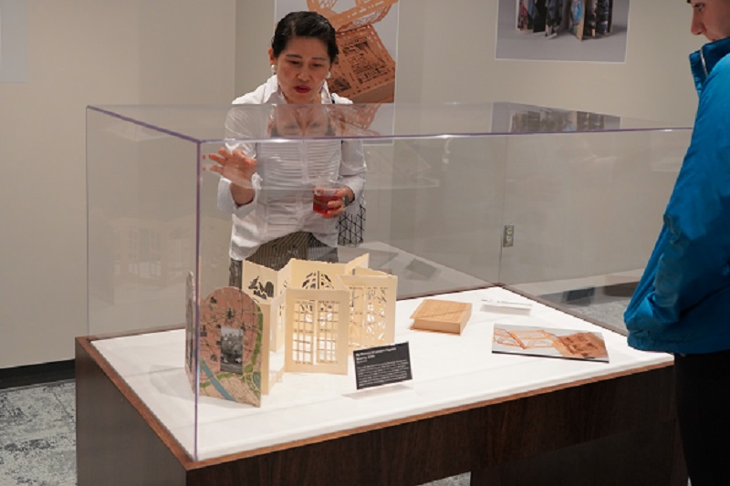 Narae Kim stands behind a display case that holds one of her artist books.