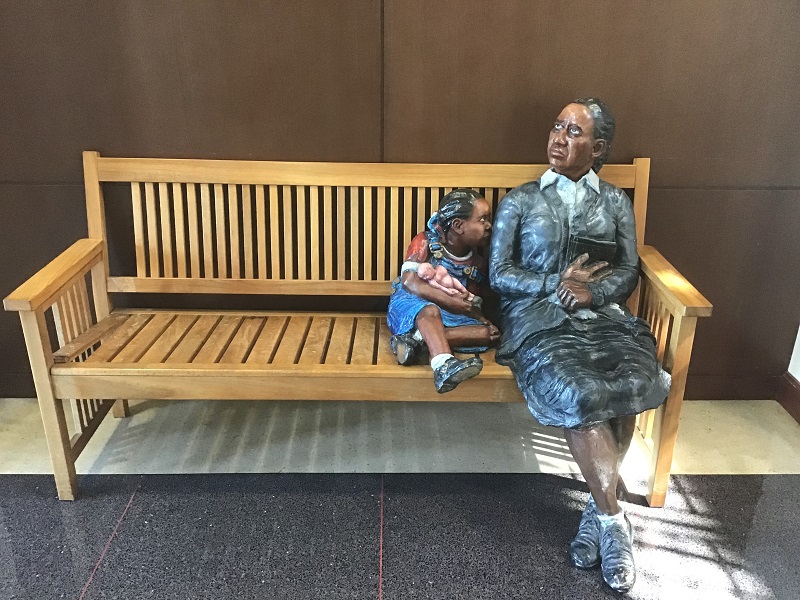 Photo of Kyle Phelps sculpture "Waiting for Justice," depicting an African American woman and child on a bench outside a courtroom.