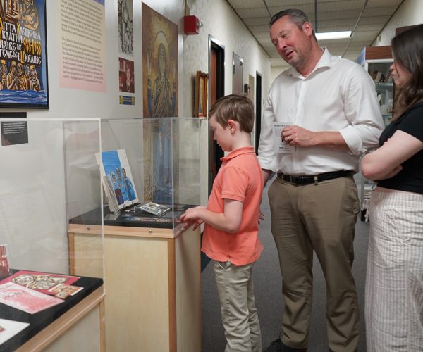 Young boy, girl and father looking intently at an exhibit case.