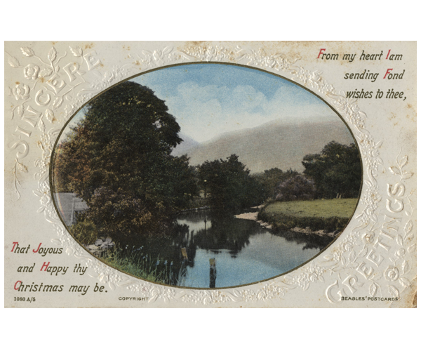 A Christmas postcard featuring an oval-shaped nature image including a pond, a grove of trees and a boathouse. The image is surrounded by a gold foil border. Around the perimeter of the card are embossed flowers and flower garland with an embossed Christmas message, "Sincere Greetings," which is split between the top left and bottom right. A Christmas message is printed starting at the top right that reads, "From my heart I am sending fond wishes to thee," and continues at the bottom left with, "That joyous and Happy thy Christmas may be.”