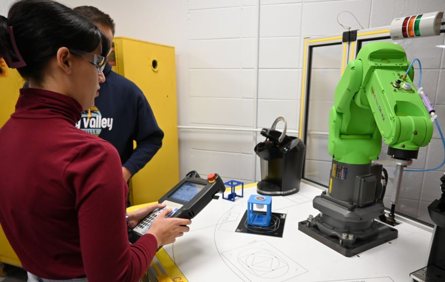 female student holding controller operating robotic arm