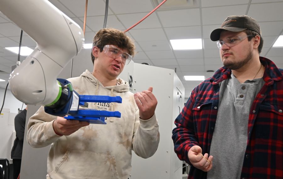Two male students working with robotic arm