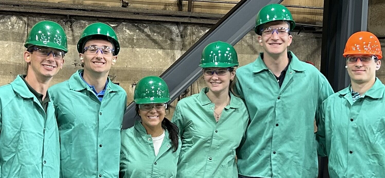 A group of students with green hard hats and jackets on