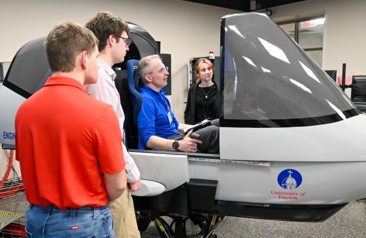 UD student team standing next to flight simulator with test pilot seated inside