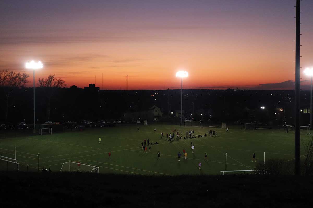 Past sunset view with pink sky across the soccer field.