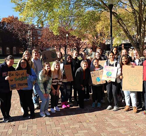 Members of the Sustainability Club stand together holding signs.